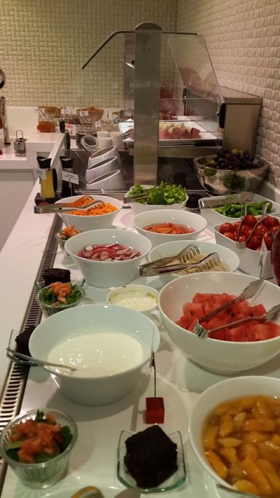 Fresh watermelon by bowls of radish and tomatoes under a bright light in Breakfast & In-Room Dining at Warwick Ankara