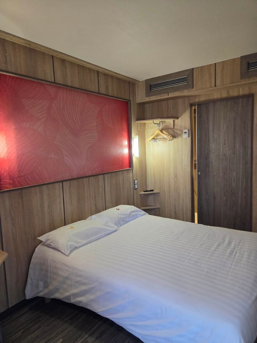 Chambre avec lit double et décoration moderne à l'Hôtel Aurillac Aéroport.