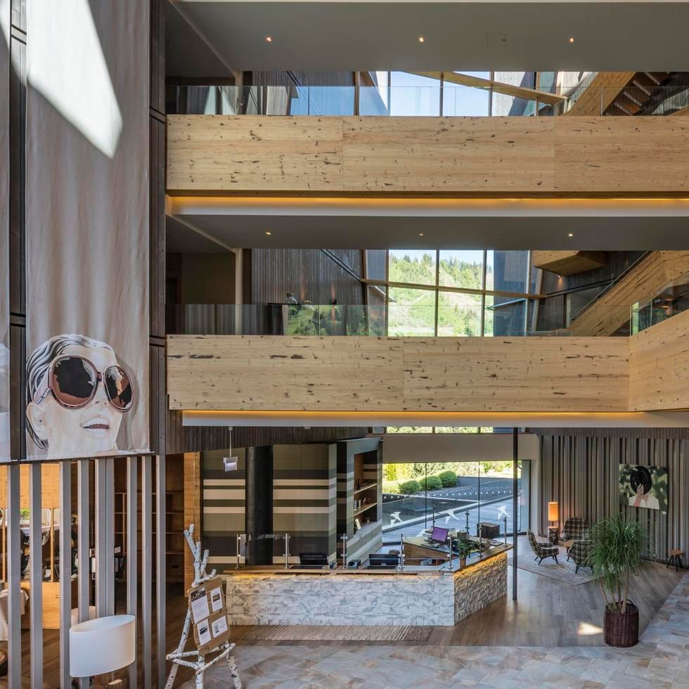 Lobby with wood paneling, large windows, and open multi-level design at Falkensteiner Hotel Schladming