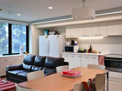 Modern kitchen and dining area with appliances, furniture, and large windows.