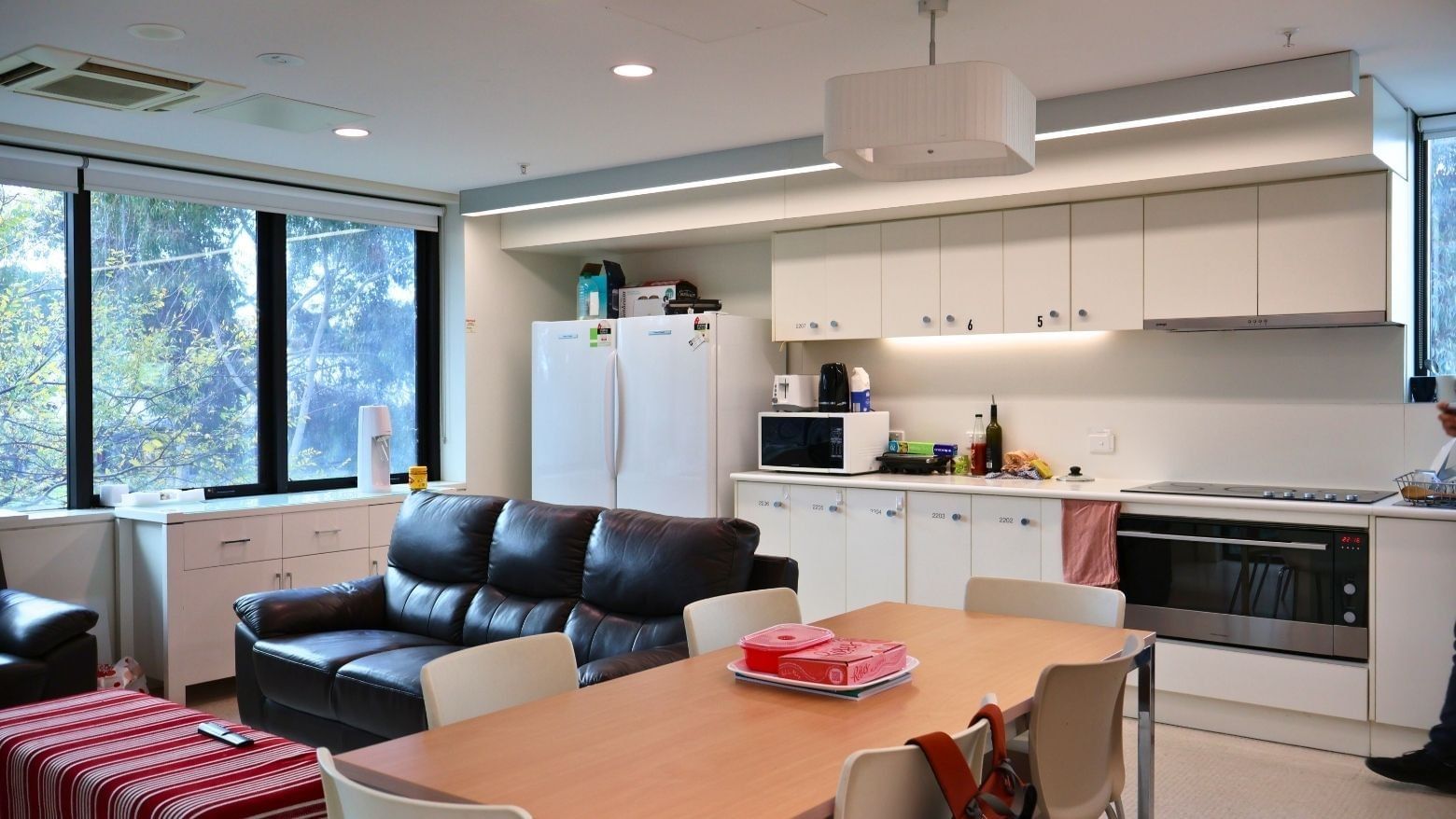 Modern kitchen and dining area with appliances, furniture, and large windows.