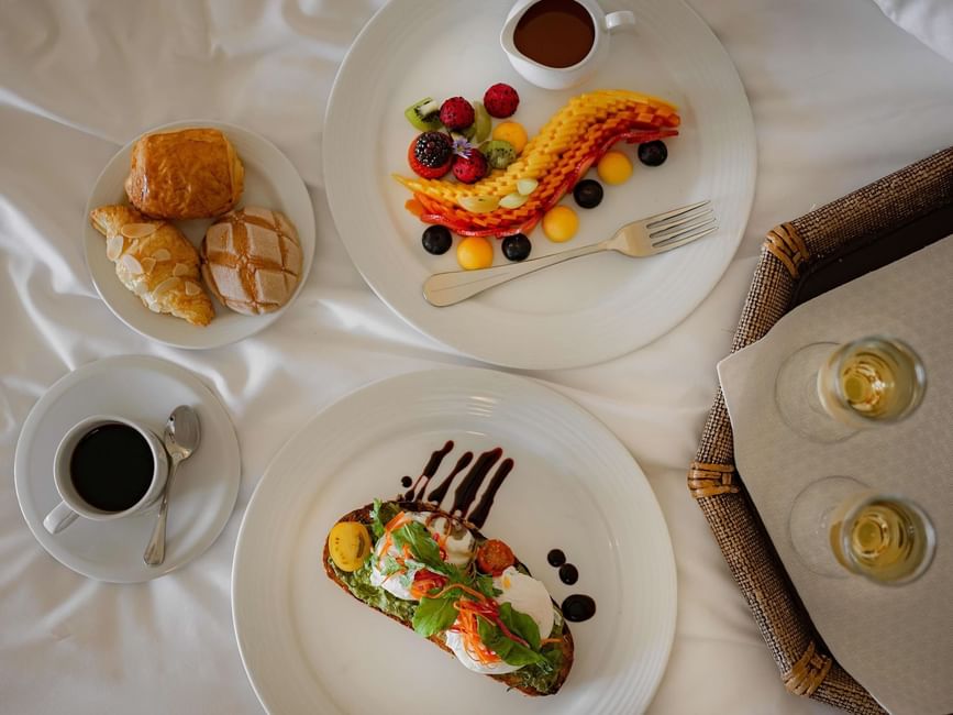 In-room breakfast featuring fresh fruit, pastries, avocado toast, and mimosas served at Marquis Los Cabos Resort