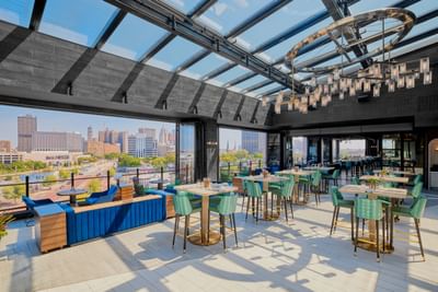 Bar & dining table arrangement with an outdoor view in IO Rooftop Lounge at Godfrey Hotel Detroit