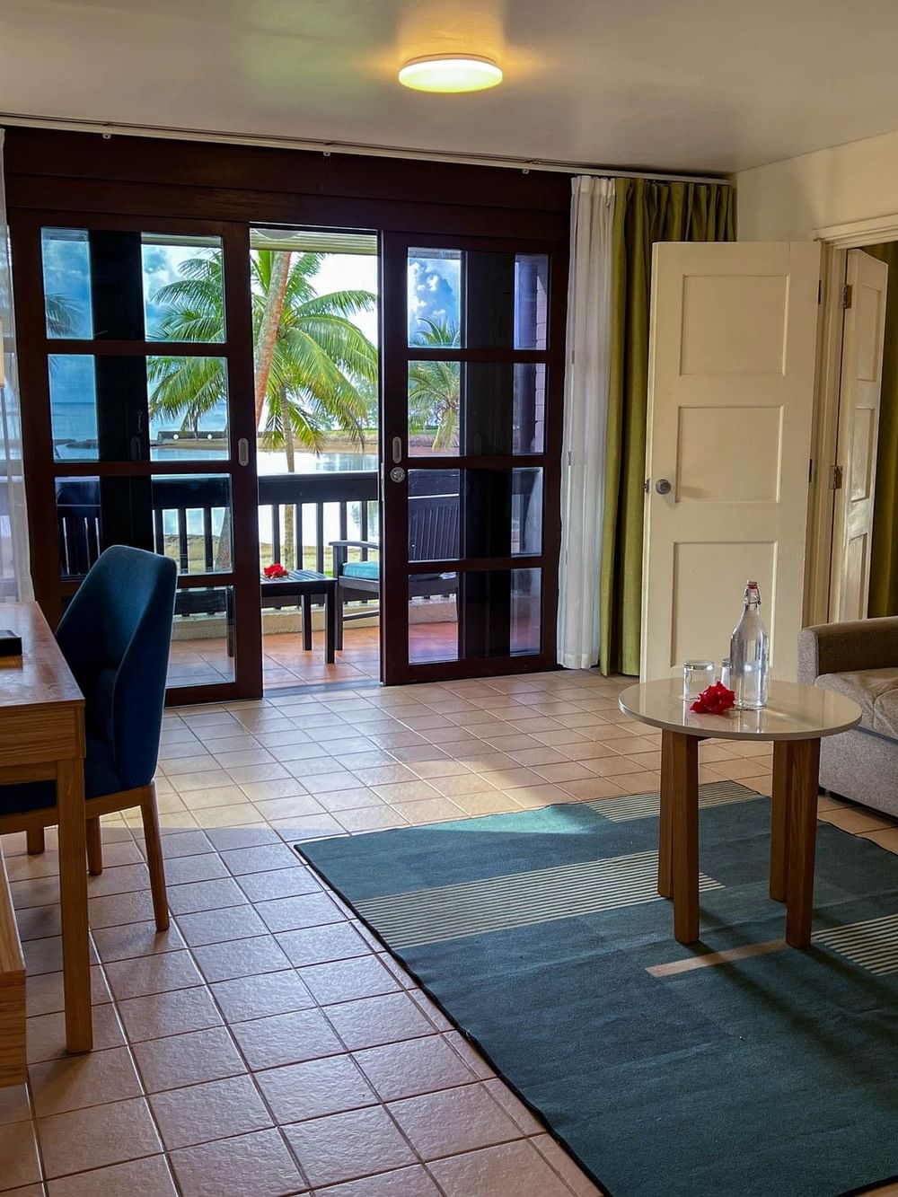 Suite at The Naviti Resort in Korolevu with living area and balcony overlooking palm trees.