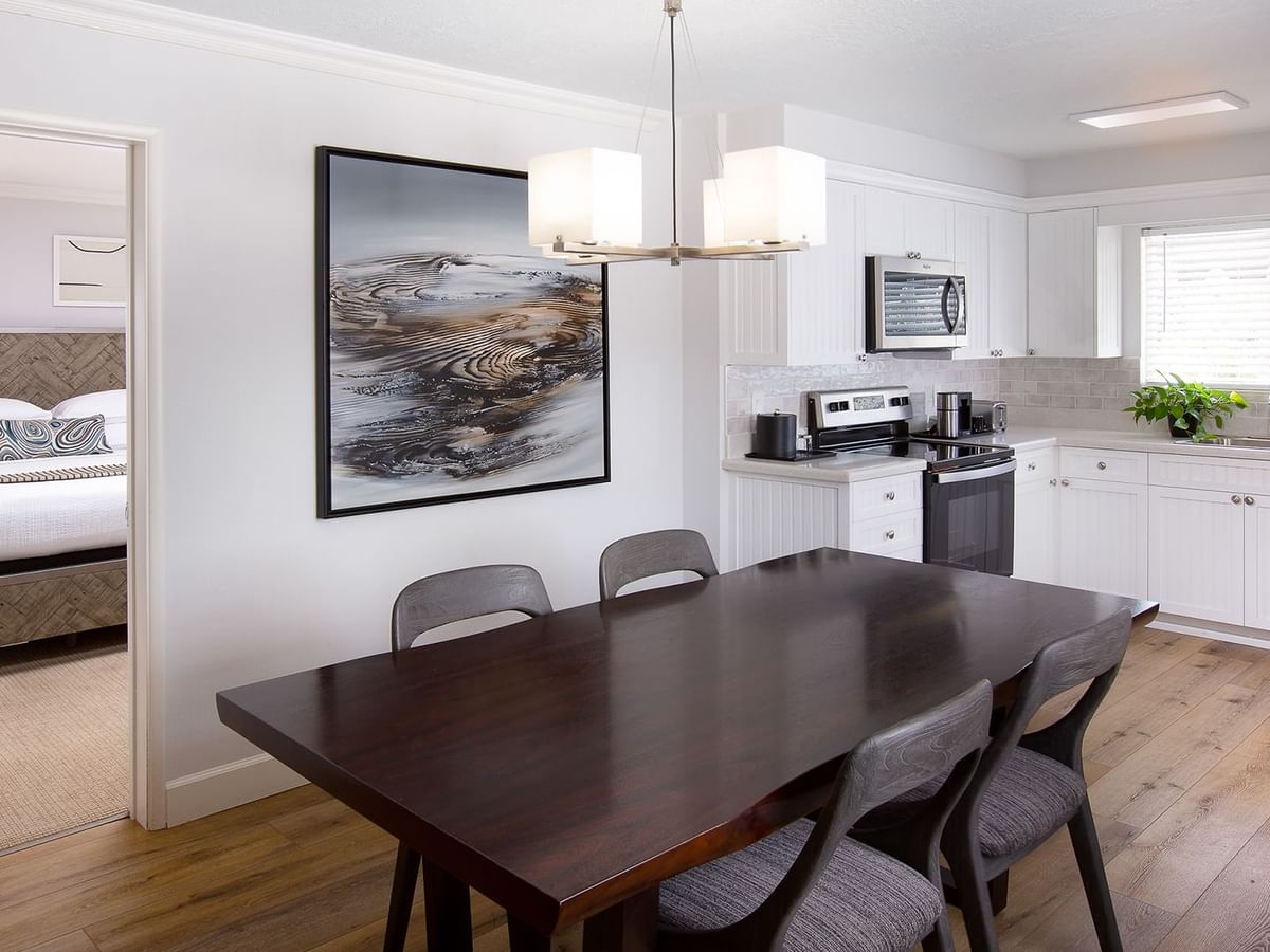 Hotel suite bedroom and kitchen with dining table, artwork, microwave, and bed in the background.