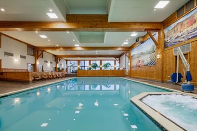 Expansive indoor swimming pool and whirlpool at Lake Placid Club Grandview features wood-paneled walls and a scenic mural