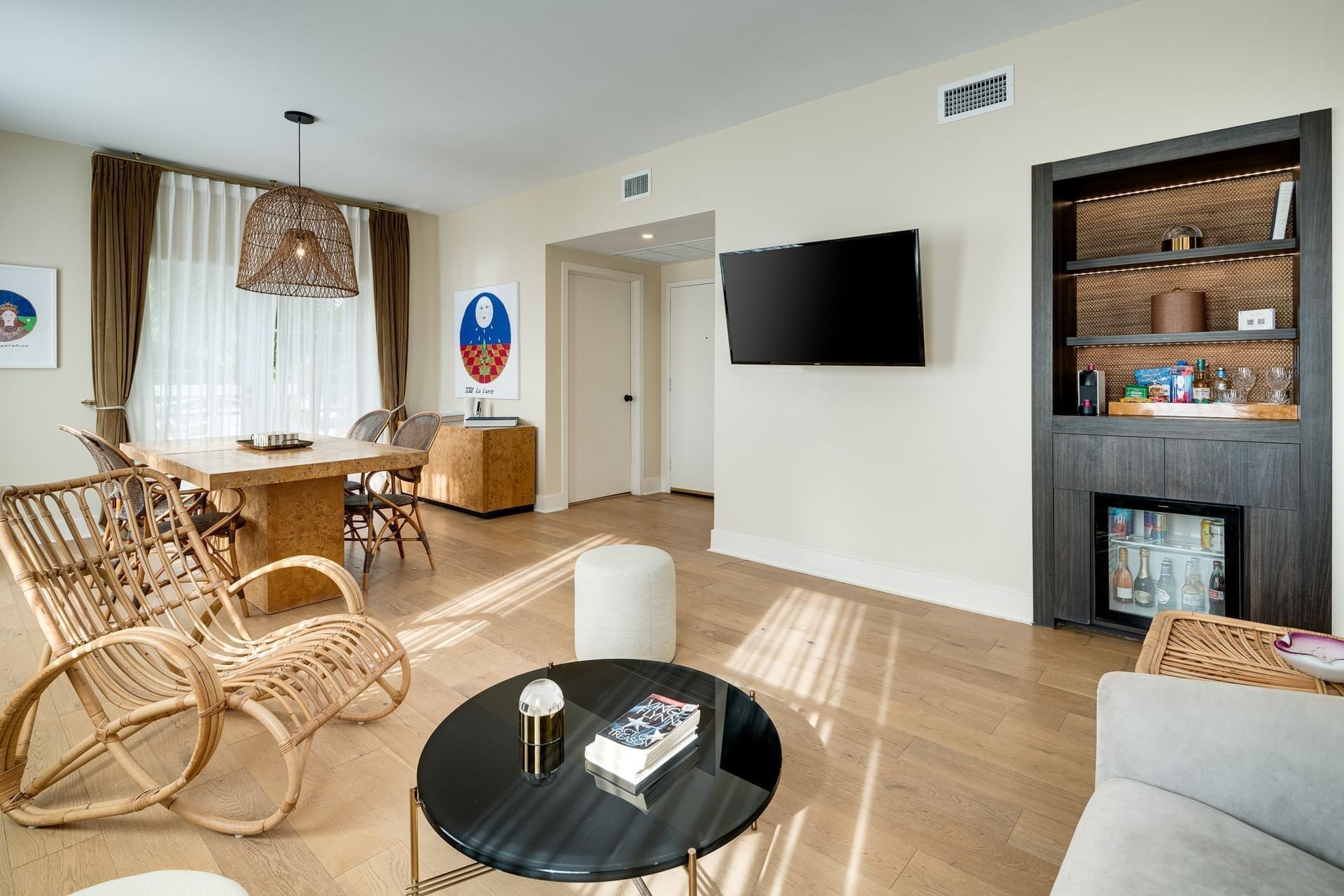 A wide view of a living room with a dining area, seating area, and large window.