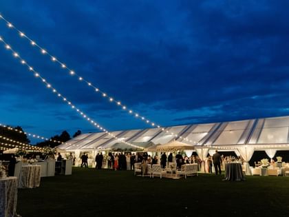Illuminated tent with wedding guests on the Camp Creek Driving Range at Camp Creek Inn, Inlet Beach.