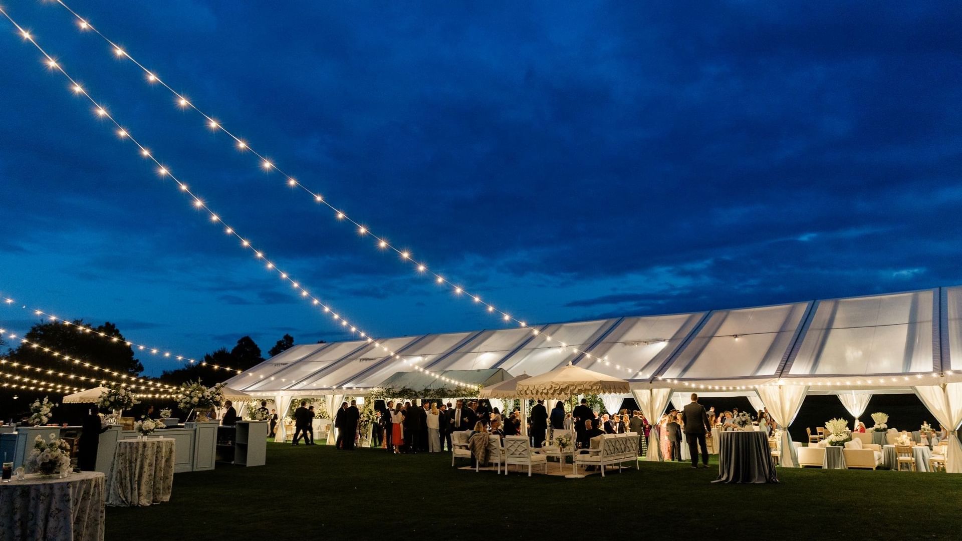 Illuminated tent with wedding guests on the Camp Creek Driving Range at Camp Creek Inn, Inlet Beach.