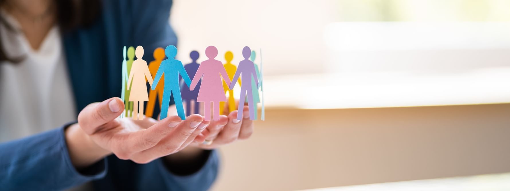 Hands gently holding colorful paper cutouts of diverse people linked together at Ibis Adelaide