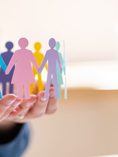 Hands gently holding colorful paper cutouts of diverse people linked together at Ibis Adelaide