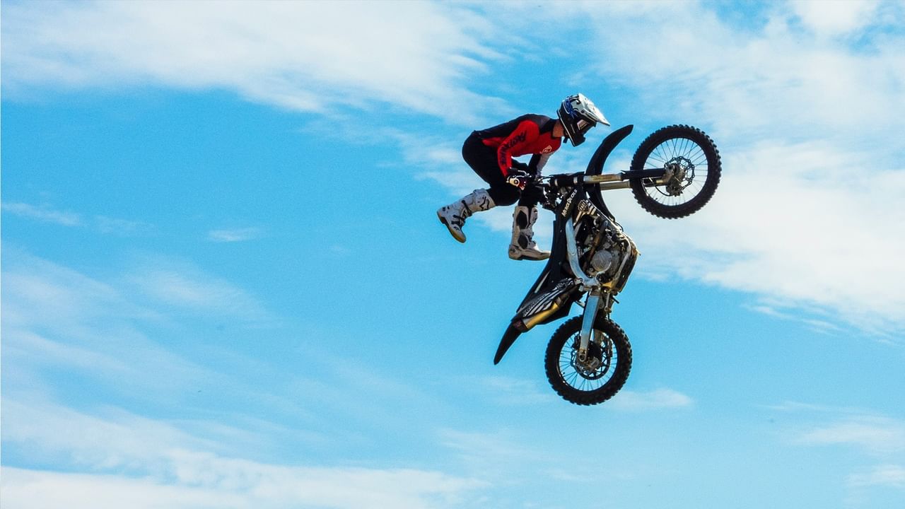 A motorcyclist performs an air stunt with a dirt bike at Monster Madness & FMX World Tour.