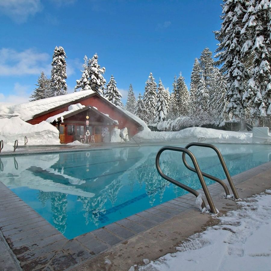 Year-round heated outdoor swimming pool pictured on a winter day with snow in the background