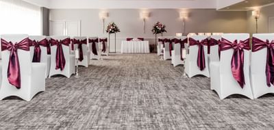 Ballroom wedding ceremony room at The Aberdeen Altens Hotel with chairs in white covers and fuchsia ribbons