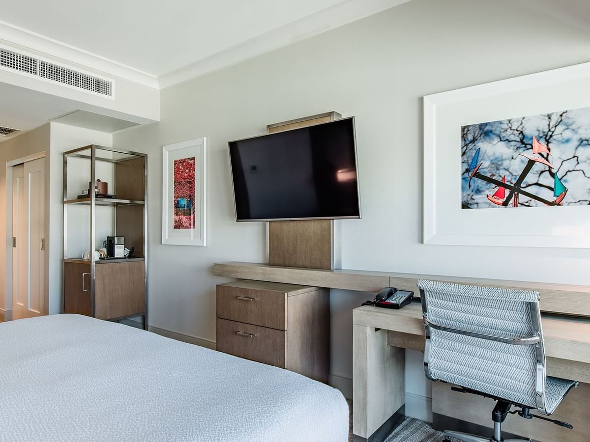 Hotel guestroom with king bed, TV, and desk