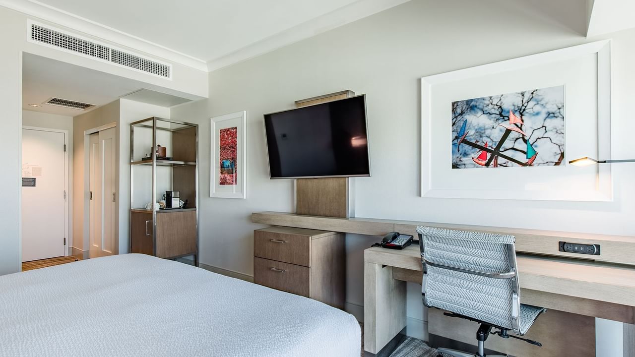 Hotel guestroom with king bed, TV, and desk