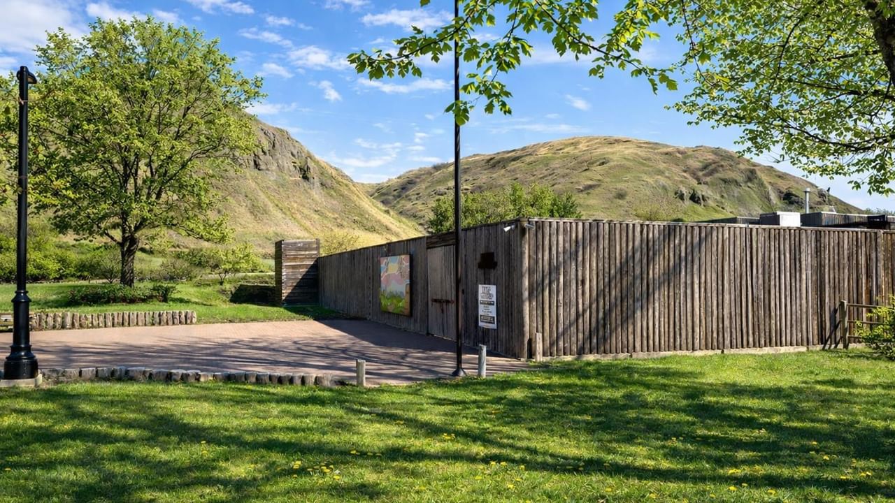 Fort Whoop-Up historical site with a wooden wall and surrounding greenery.