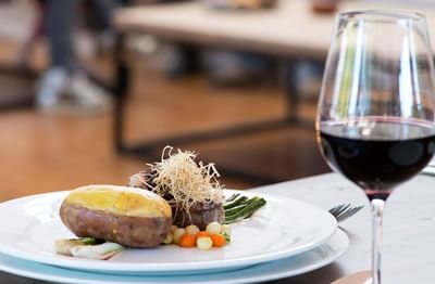 Plated meal with a glass of red wine served in Ensamblaje Restaurant, best dining Santa Cruz at NOI Blend Colchagua