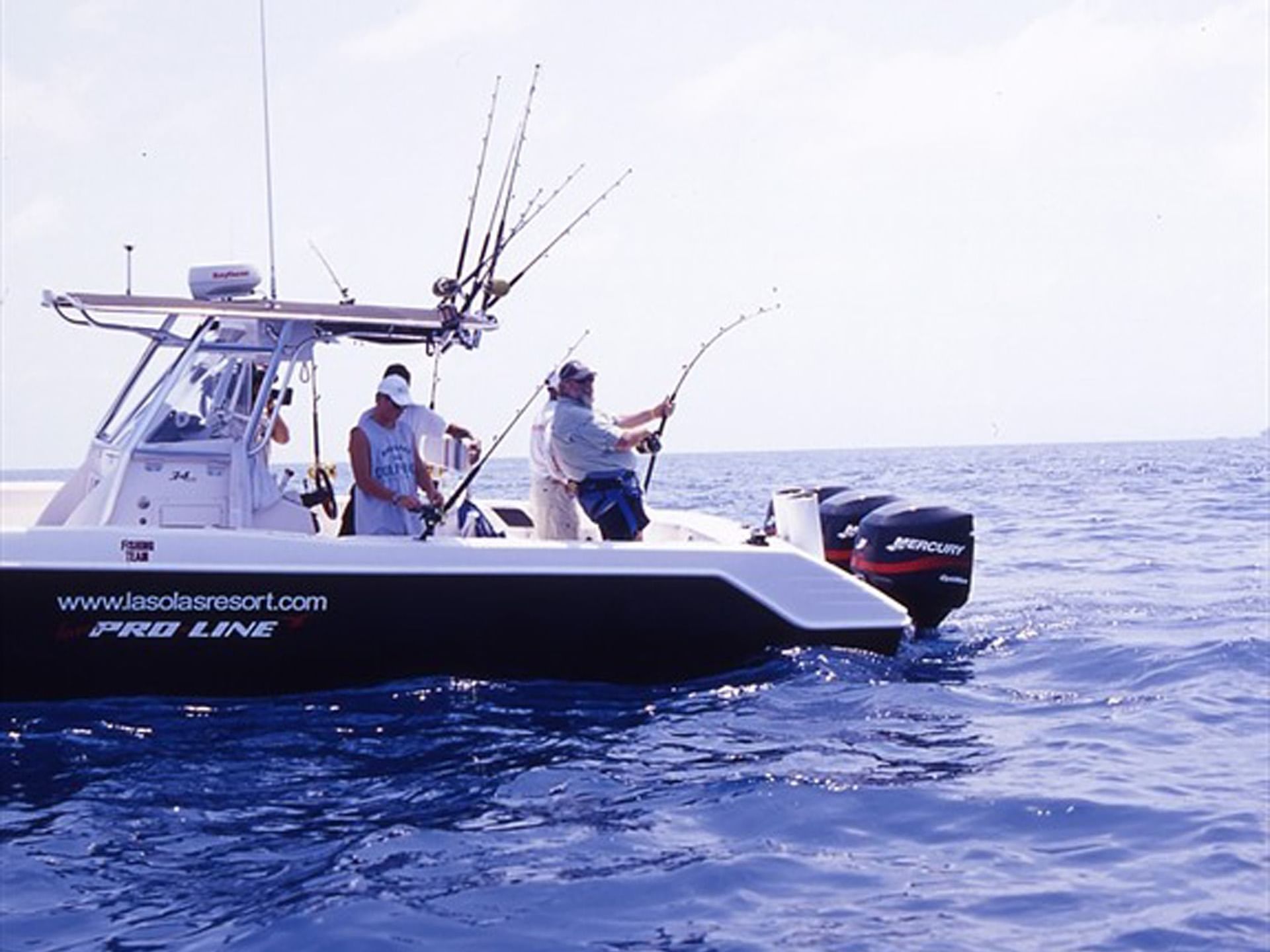 Group of people fishing on a boat at sea with fishing rods lined up near Las Olas Beach Resort