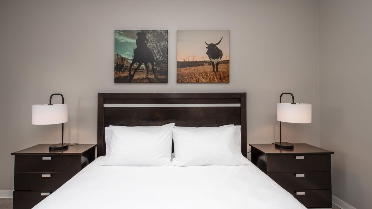 King bed at Coast Innisfail Hotel with bedside lamps and artwork