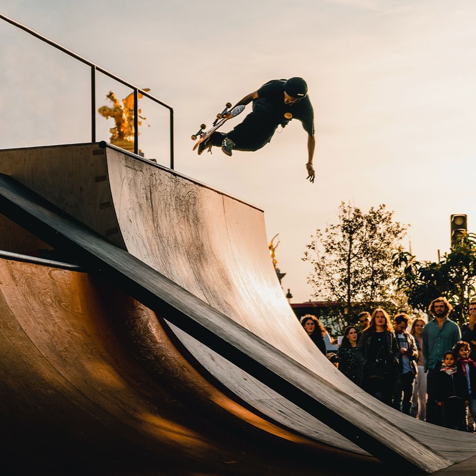 Skateboarder mid-air over a ramp at sunset with onlookers at Falkensteiner Hotel Bratislava