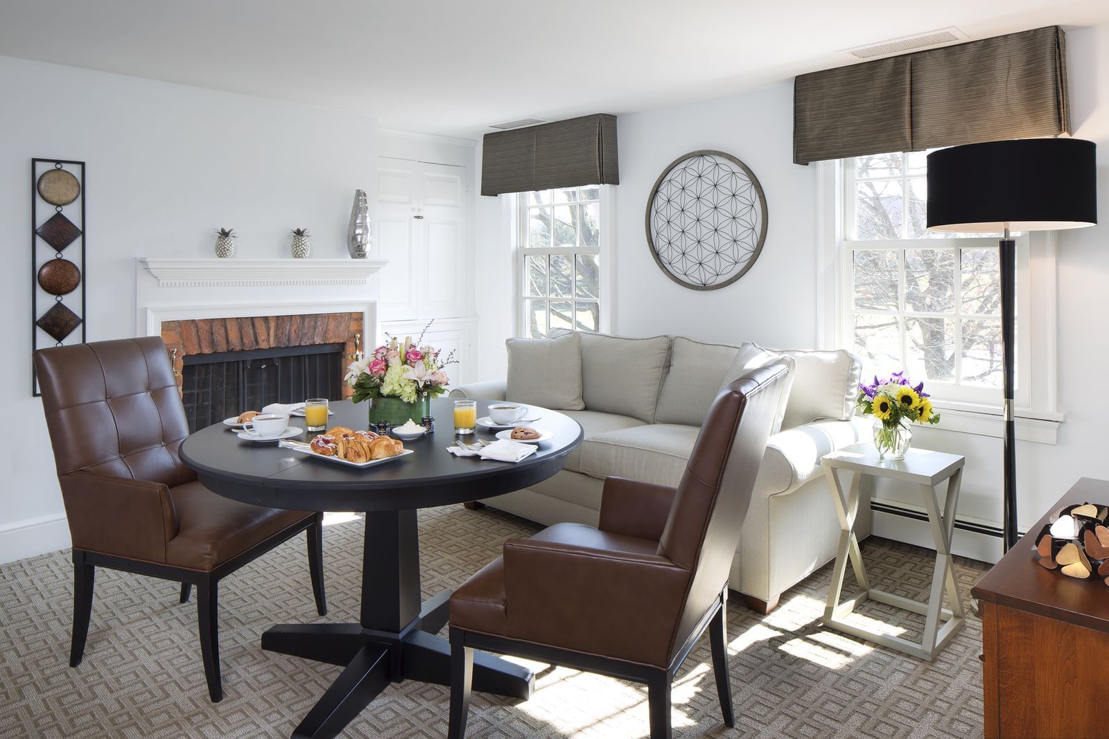 Bright suite with round dining table, leather chairs, beige sofa, and fireplace at Aramark Chauncey Conference Center