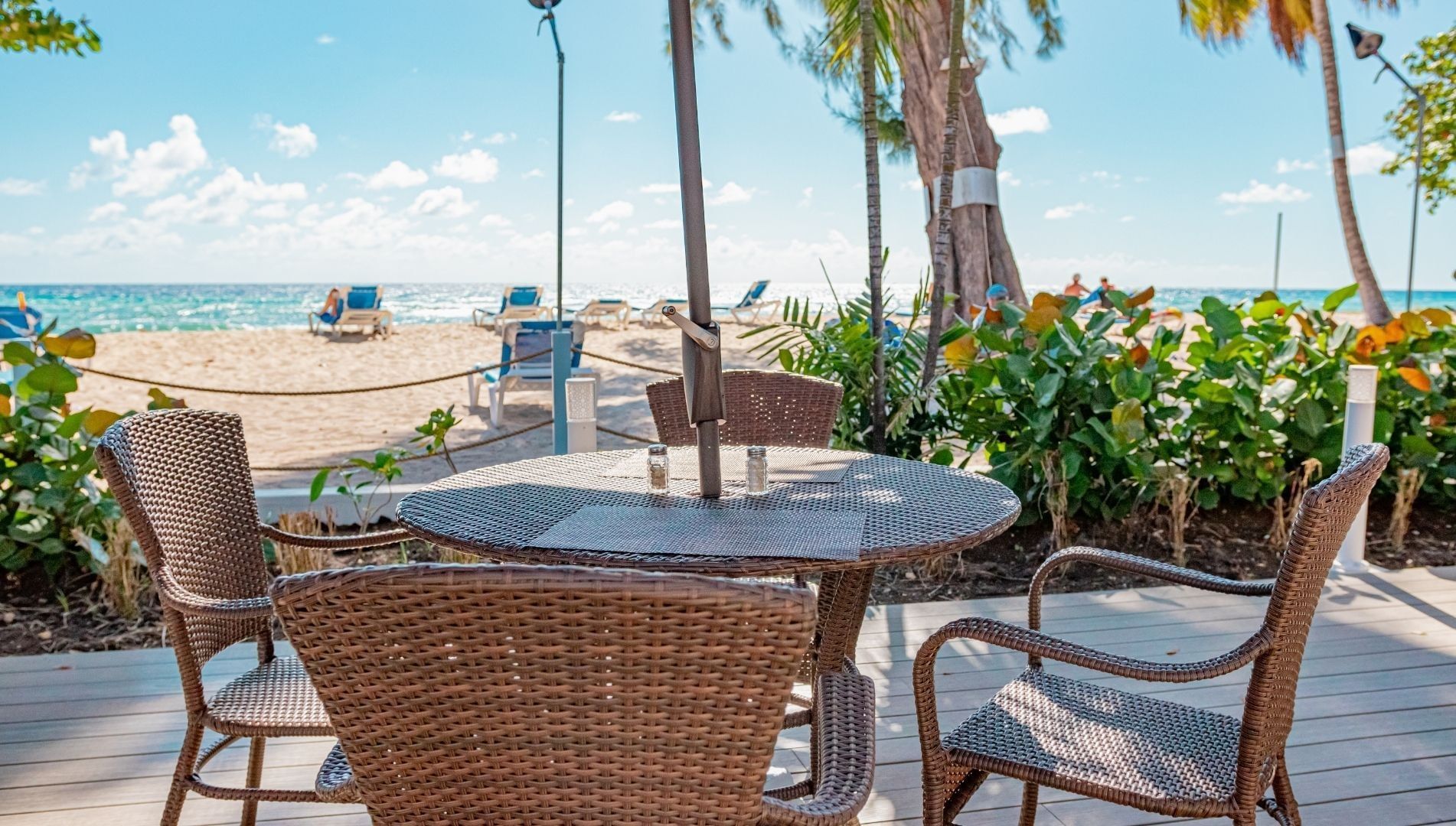 Wicker chairs around a table under an umbrella pole at Savannah Beach Hotel, the top Barbados all-inclusive family resorts