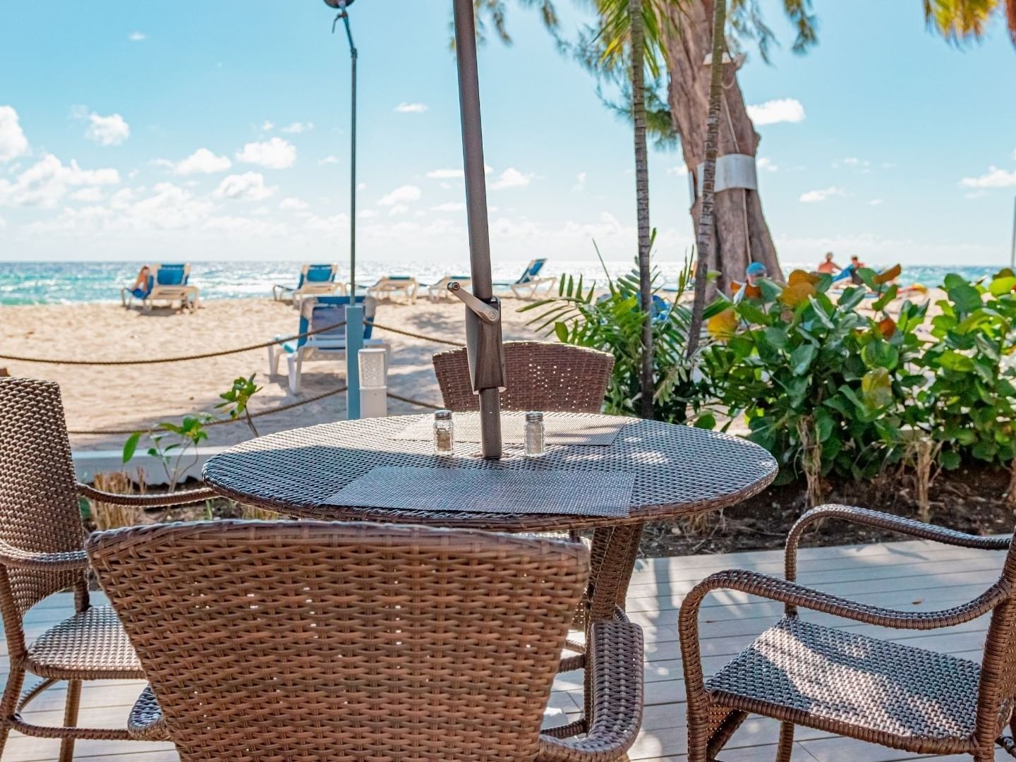 Outdoor table with chairs on a wooden deck overlooking the beach at Savannah Beach Hotel.