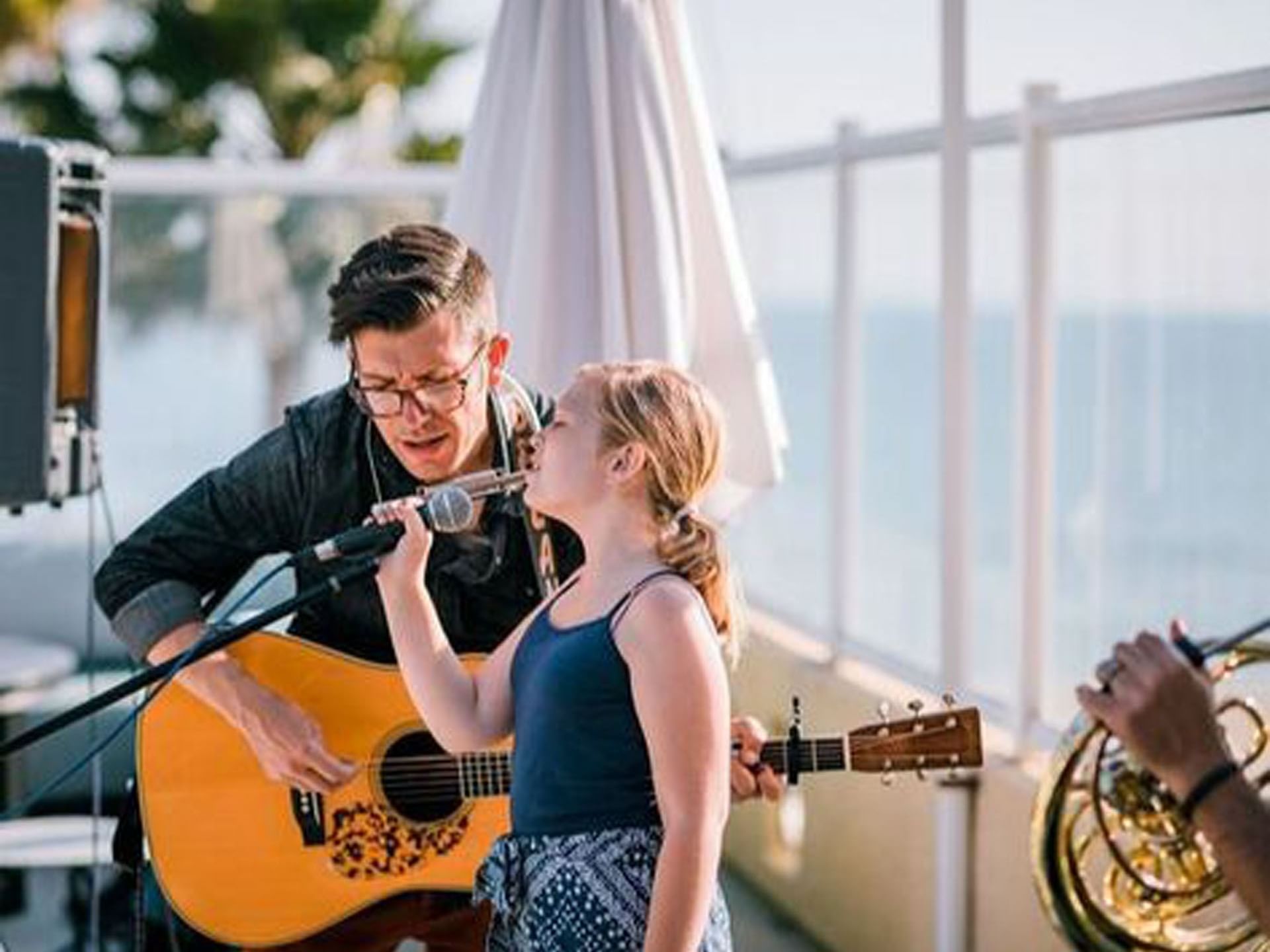 Guitarist playing guitar & singing next to a young girl on stage at SeaCrest Oceanfront Hotel Pismo Beach