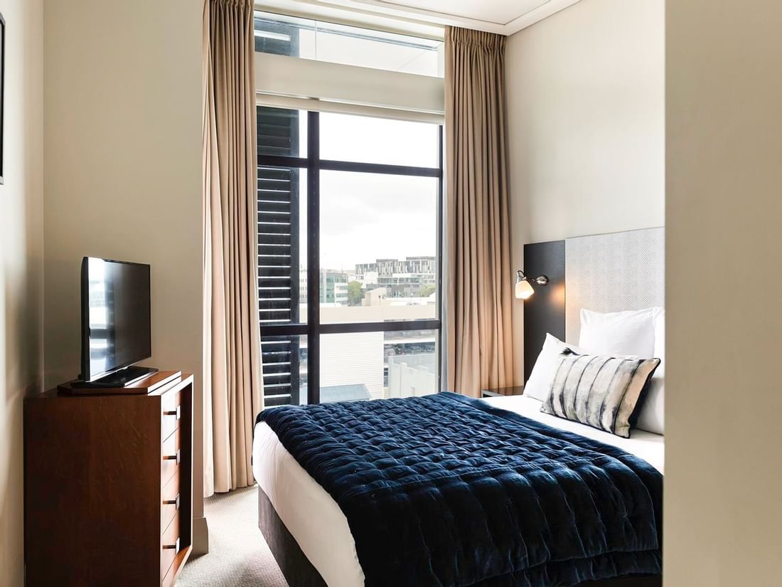 TV facing bed by the window in the City View One Bedroom Suite at The Sebel Auckland Viaduct Harbour