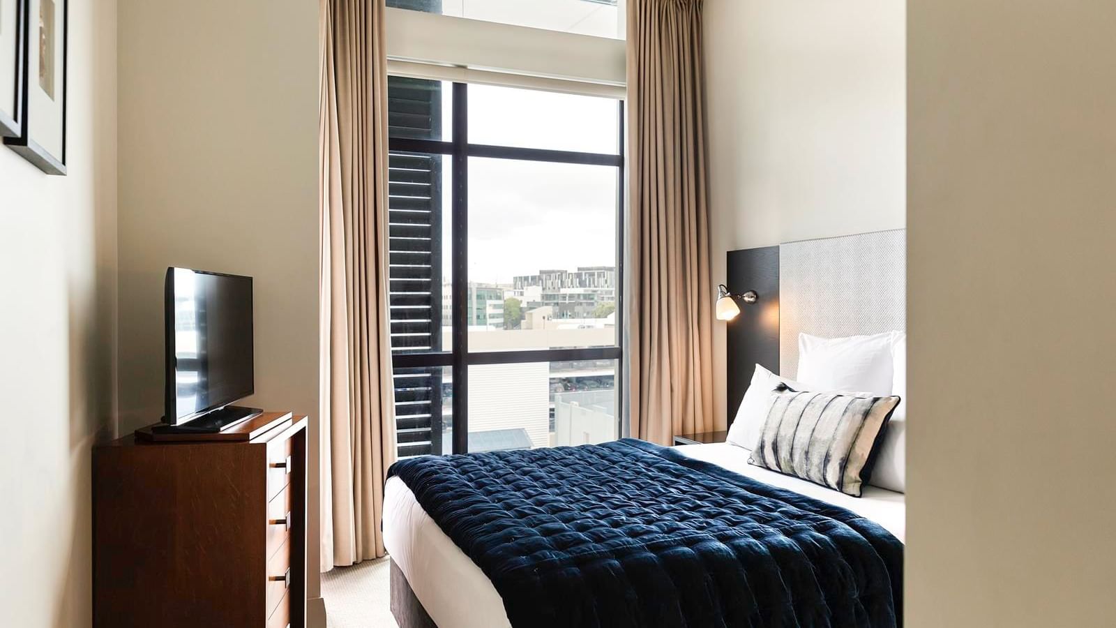 TV facing bed by the window in the City View One Bedroom Suite at The Sebel Auckland Viaduct Harbour