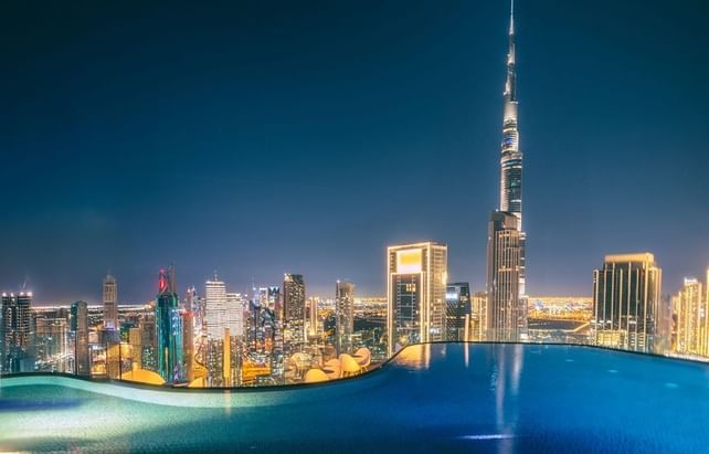 Relaxing rooftop infinity pool at Paramount Hotel Midtown, overlooking a stunning skyline and the Burj Khalifa