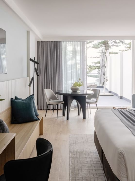 Ocean View Terrace King at Elysium Manly with a dining set by a lounge bench under a TV, offering cozy Manly accommodation