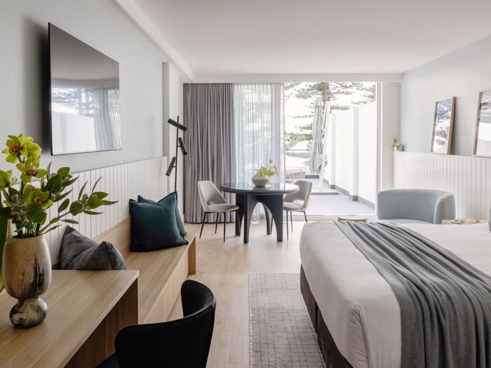 Ocean View Terrace King at Elysium Manly with a dining set by a lounge bench under a TV, offering cozy Manly accommodation