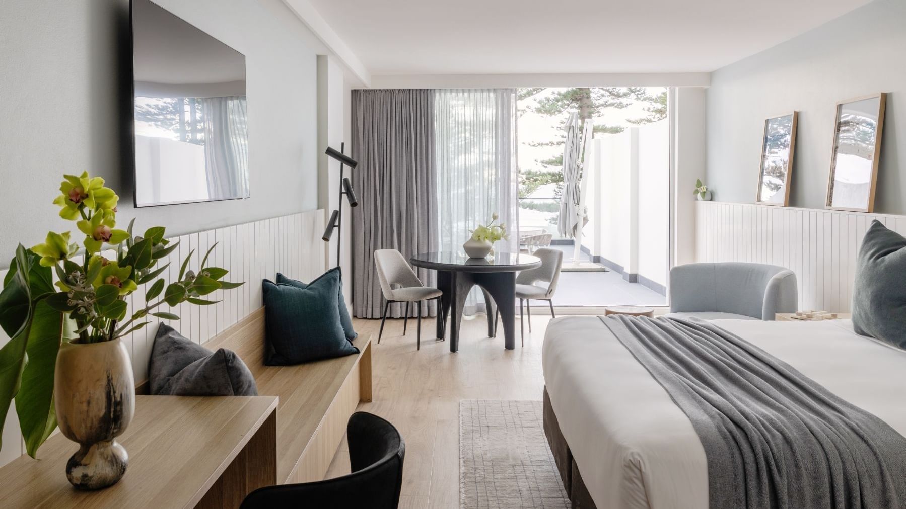 Ocean View Terrace King at Elysium Manly with a dining set by a lounge bench under a TV, offering cozy Manly accommodation