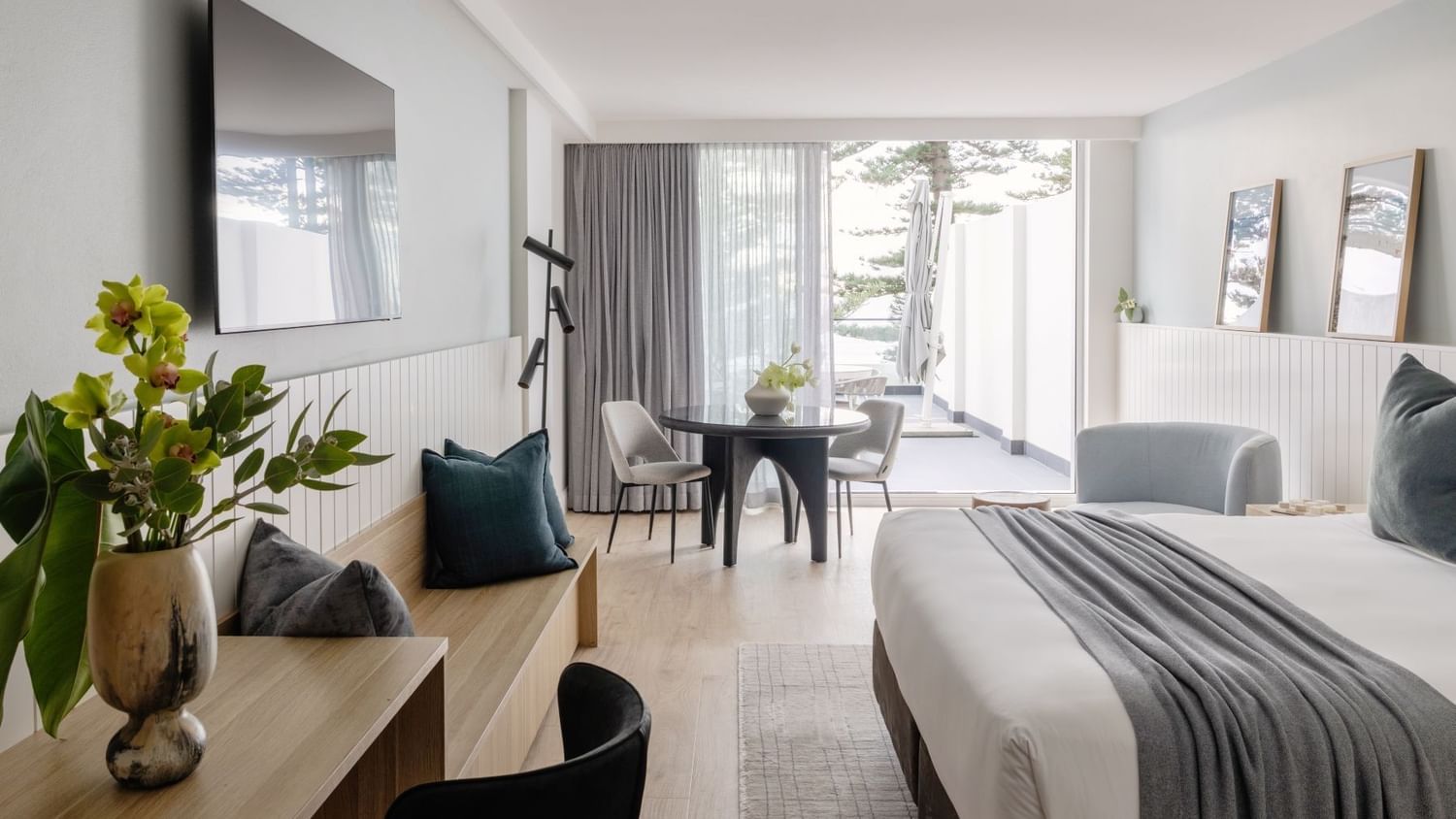 Ocean View Terrace King at Elysium Manly with a dining set by a lounge bench under a TV, offering cozy Manly accommodation