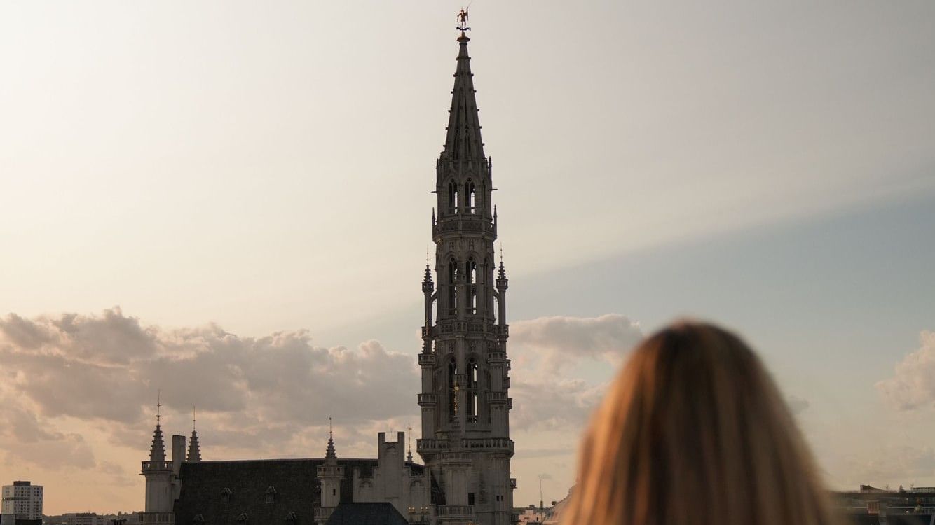 Vrouw geniet van uitzicht op de Grote Markt bij zonsondergang bij Secret Rooftop by Warwick in Brussel.