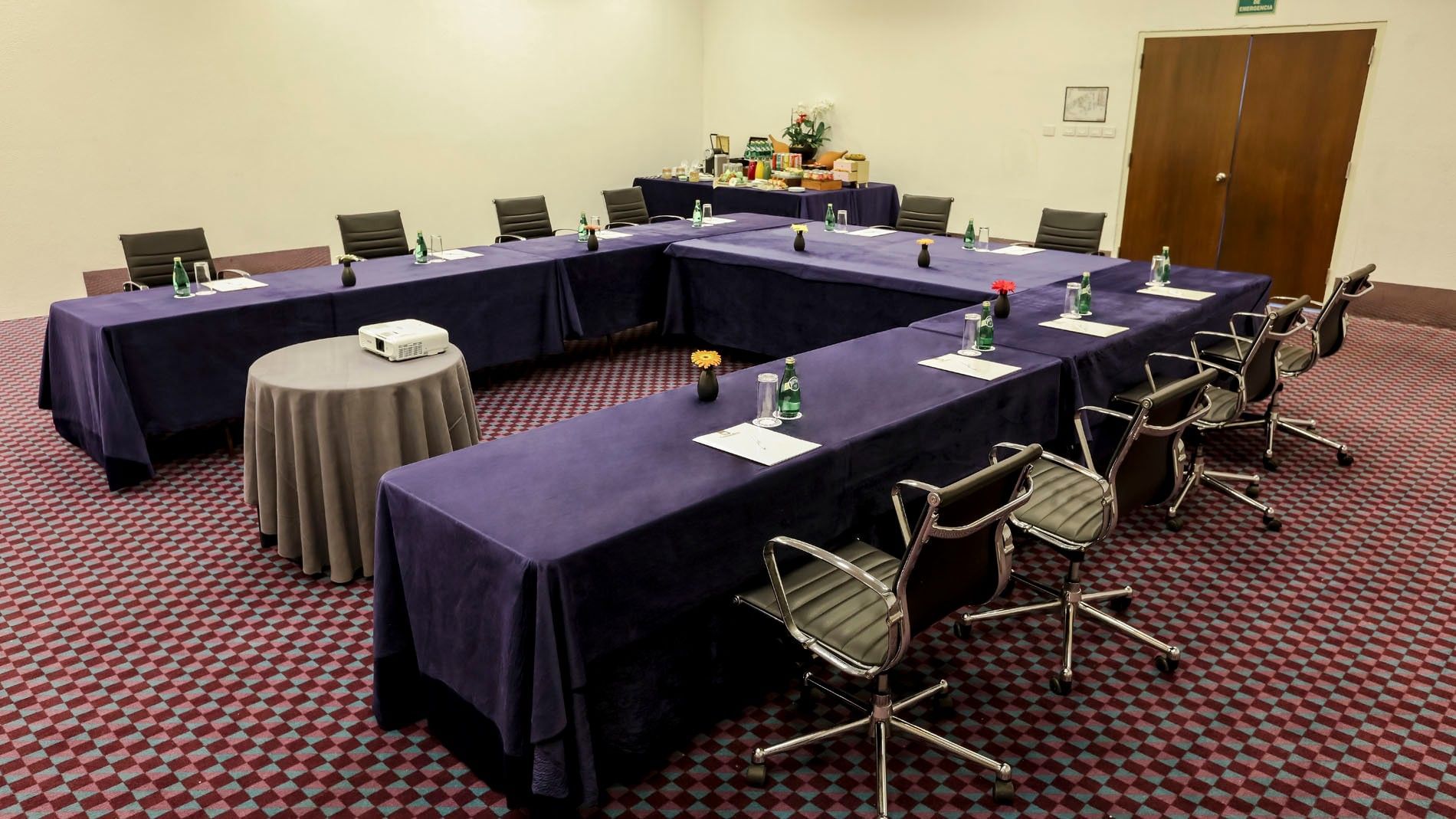 U-shaped Salón del Sol conference table with purple tablecloths and a coffee station in the corner at Camino Real Veracruz