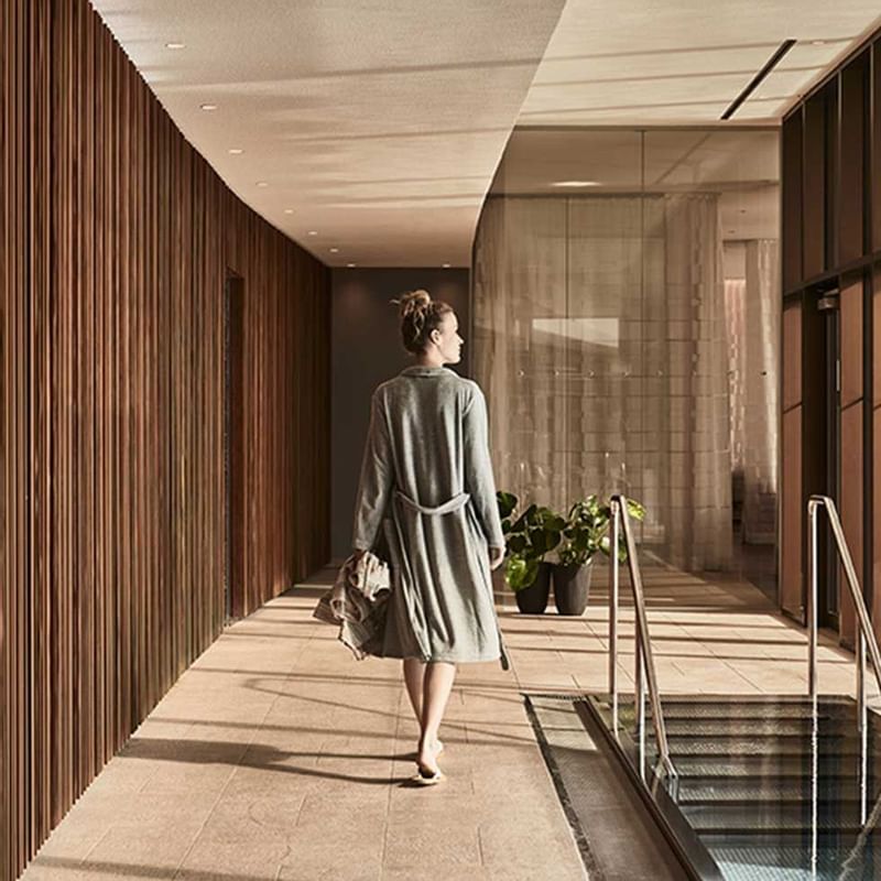 A woman walking with a bathrobe at Falkensteiner Hotels