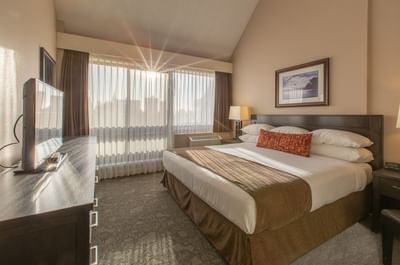 One bedroom Suite at Embassy Inn Victoria featuring a king-sized bed, a TV and bright sunlight coming from the window