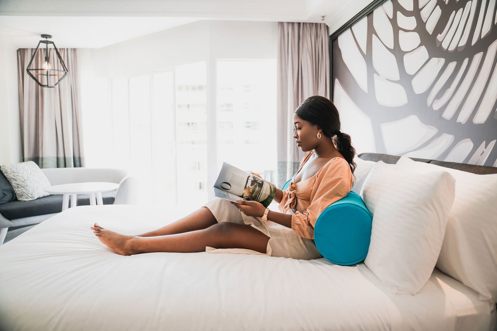 A young lady reading a magazine on a bed at Pullman Cairns