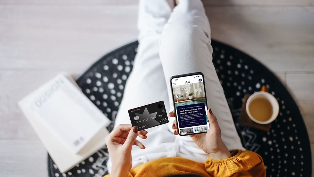 Top view of a lady holding a smartphone displaying a booking site of ALL and NAB rewards card at Novotel Sydney Olympic Park