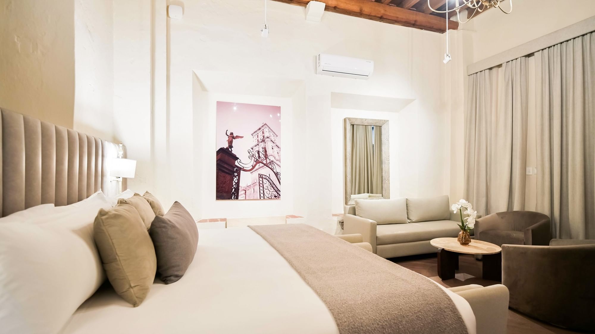 Habitación elegante con cama grande, sofá y arte en la pared en Quinta Real Puebla, Heroica Puebla de Zaragoza