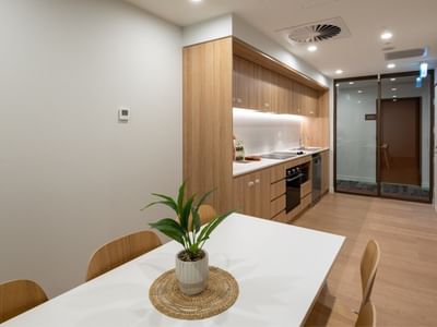 Modern kitchen and dining area with a table and potted plant at UniLodge Brisbane City.