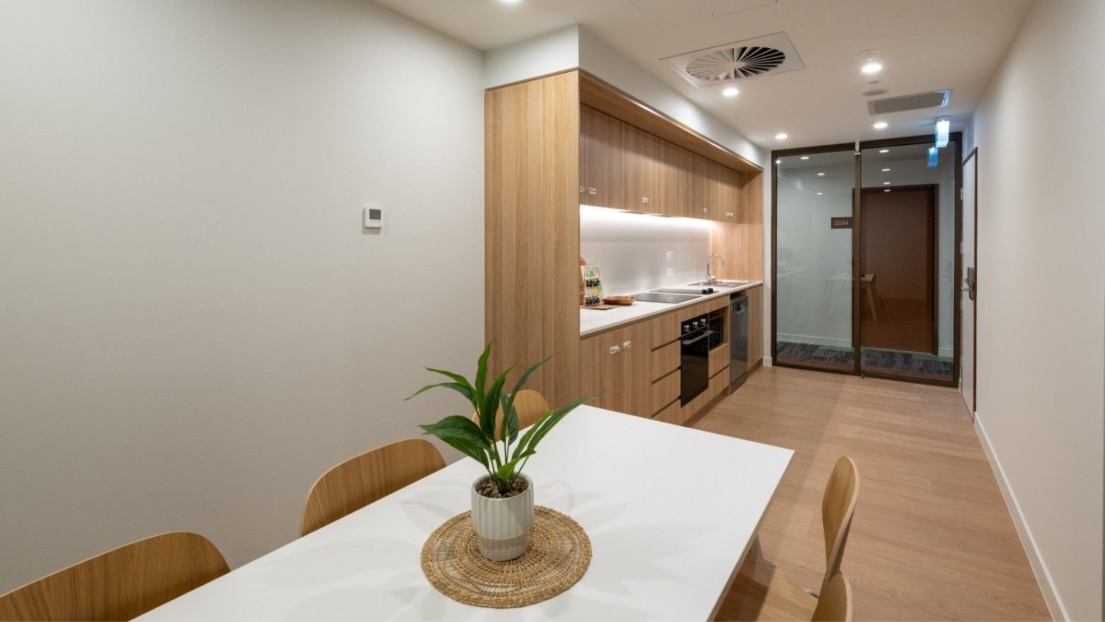 Modern kitchen and dining area with a table and potted plant at UniLodge Brisbane City.