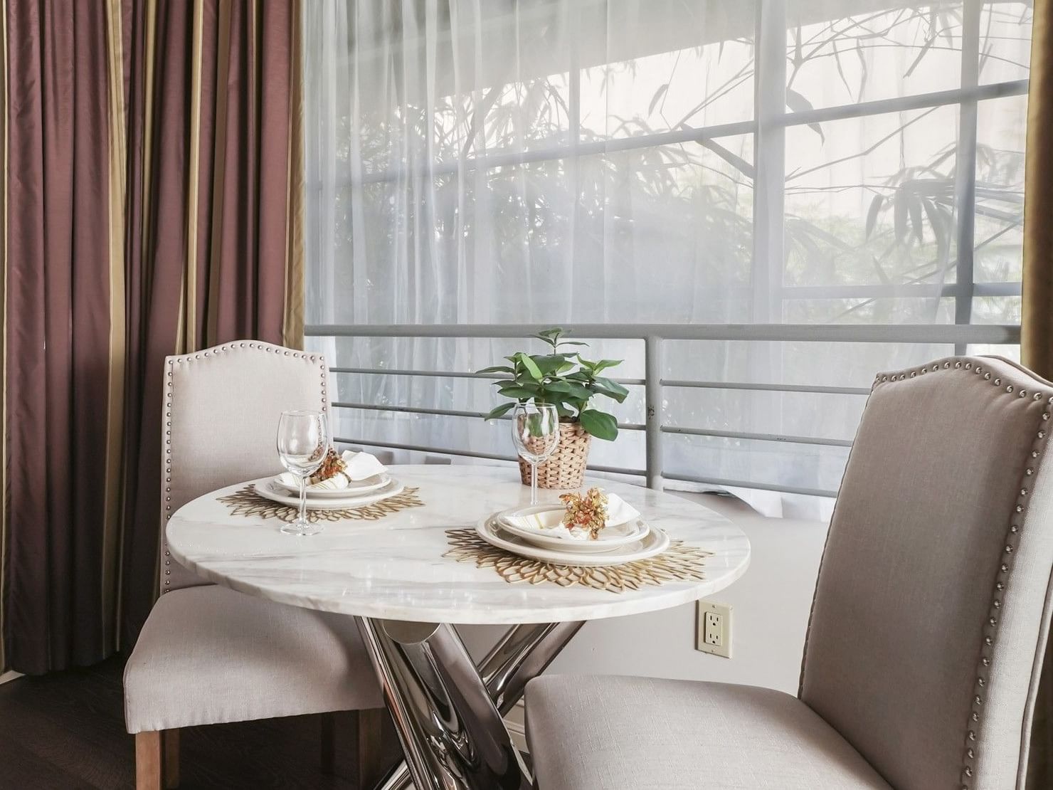 Elegant white marble dining table for two with luxury place settings in a sunlit suite at Riviera Hotel South Beach