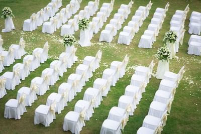 Outdoor wedding setup at The Saujana Hotel Kuala Lumpur with white chairs, flowers, and scattered petals