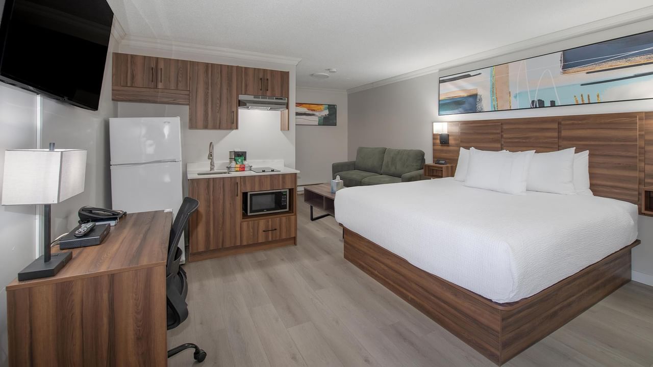 Hotel guest room with a king bed, seating area, kitchenette, work desk and flat-screen TV.