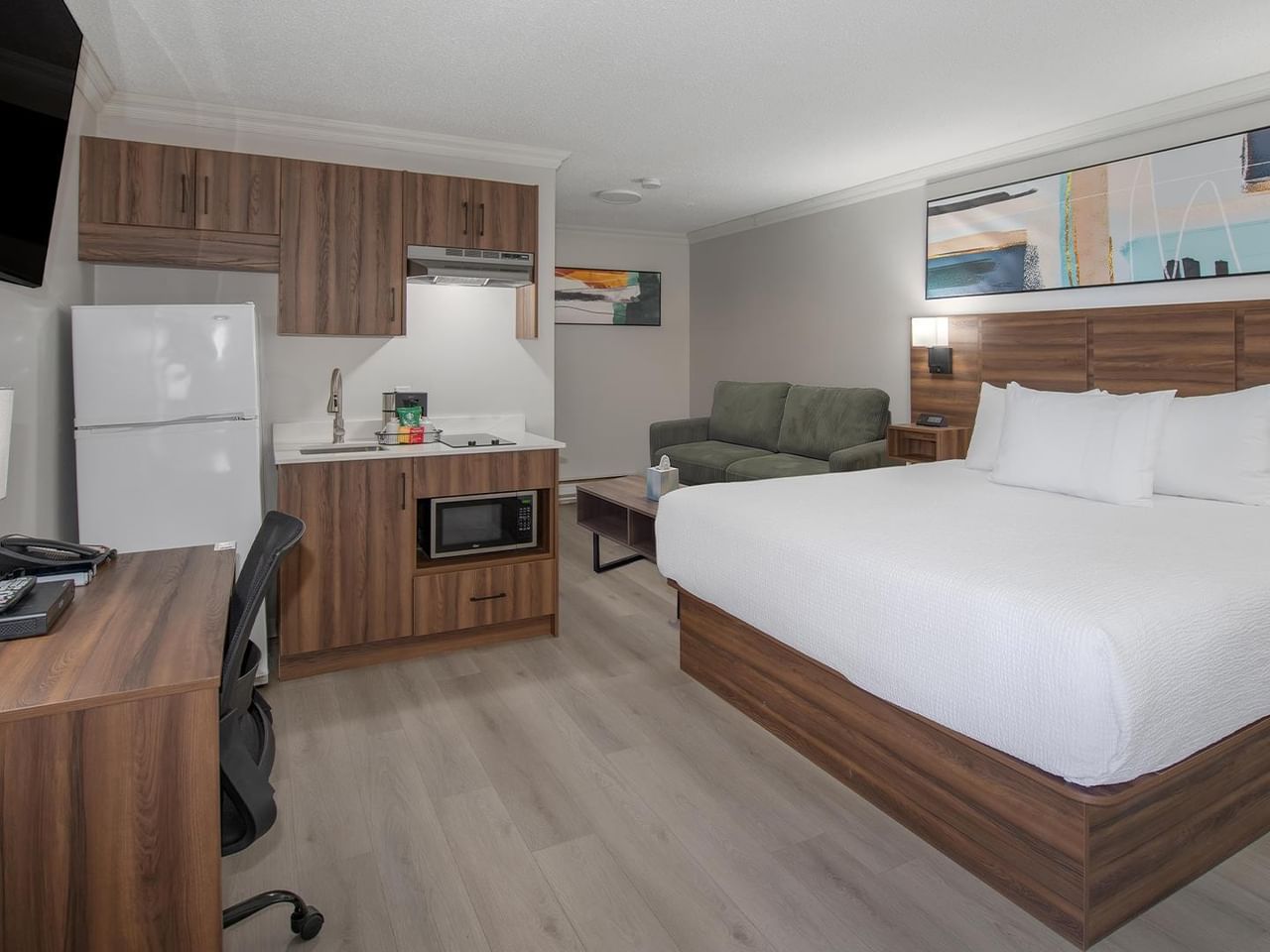 Hotel guest room with a king bed, seating area, kitchenette, work desk and flat-screen TV.