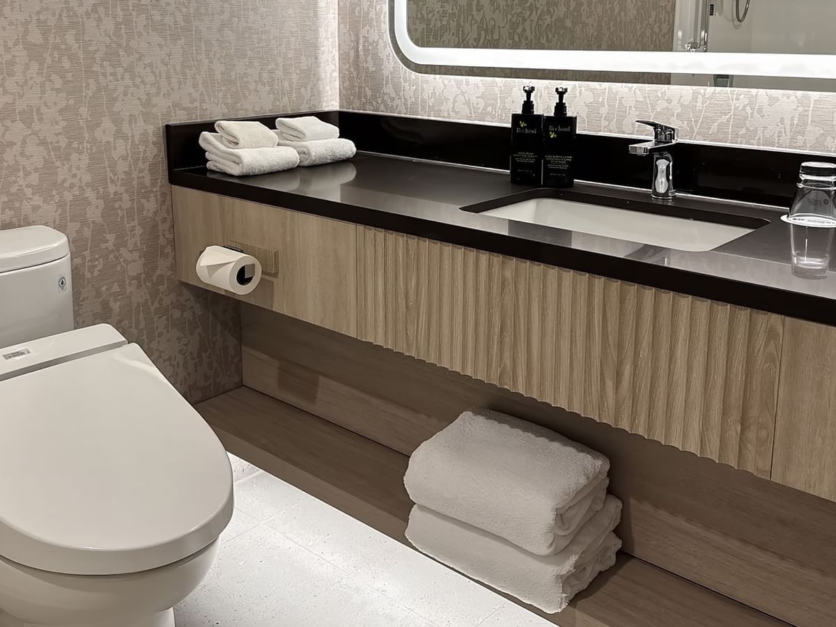 Hotel washroom with towels, sink, soap, and TOTO Washlet